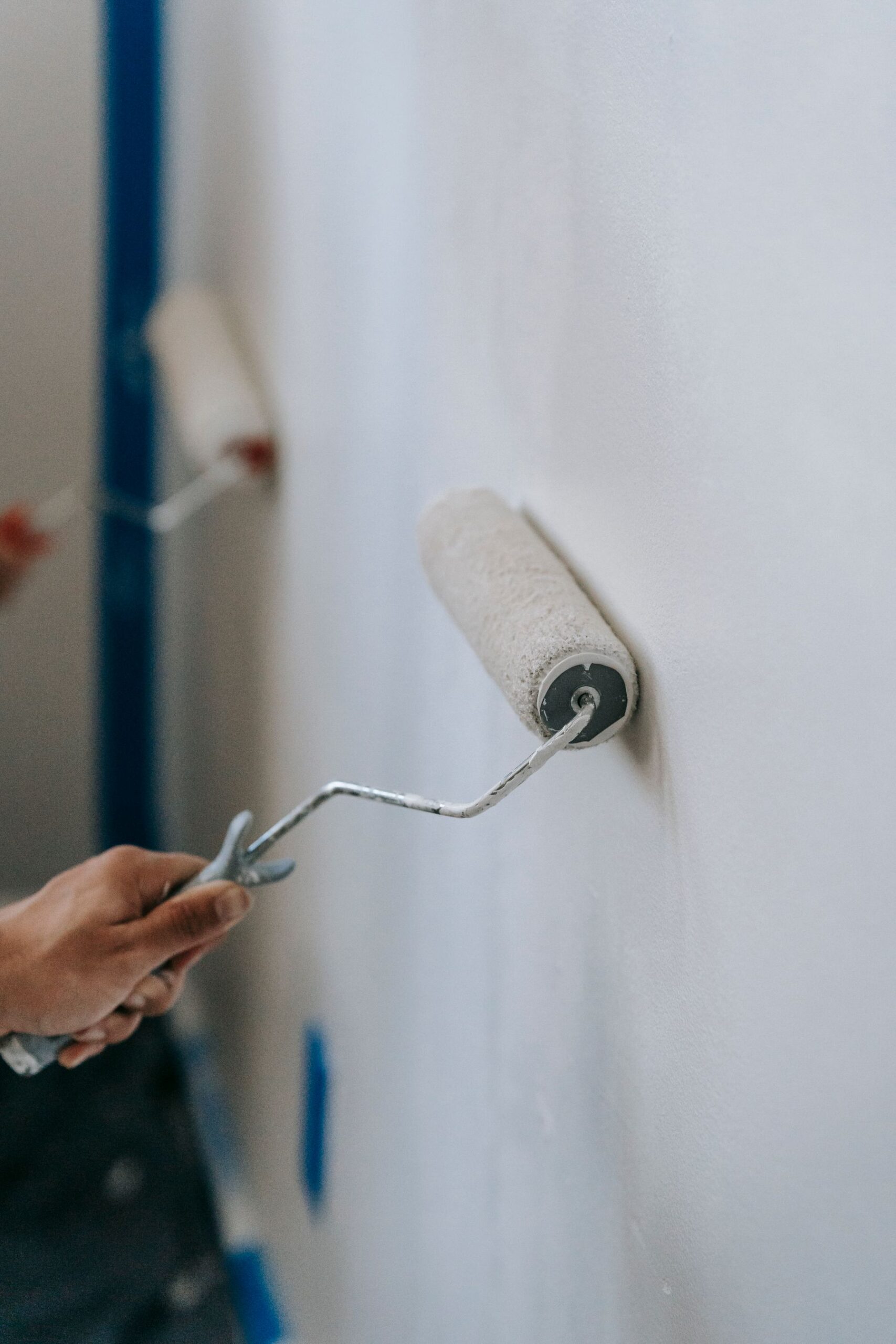 Two decorators rolling paint onto an interior wall